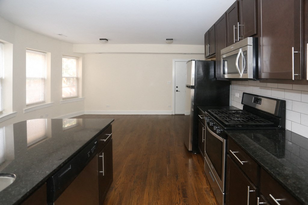 an empty kitchen with black counter tops and stainless steel appliances