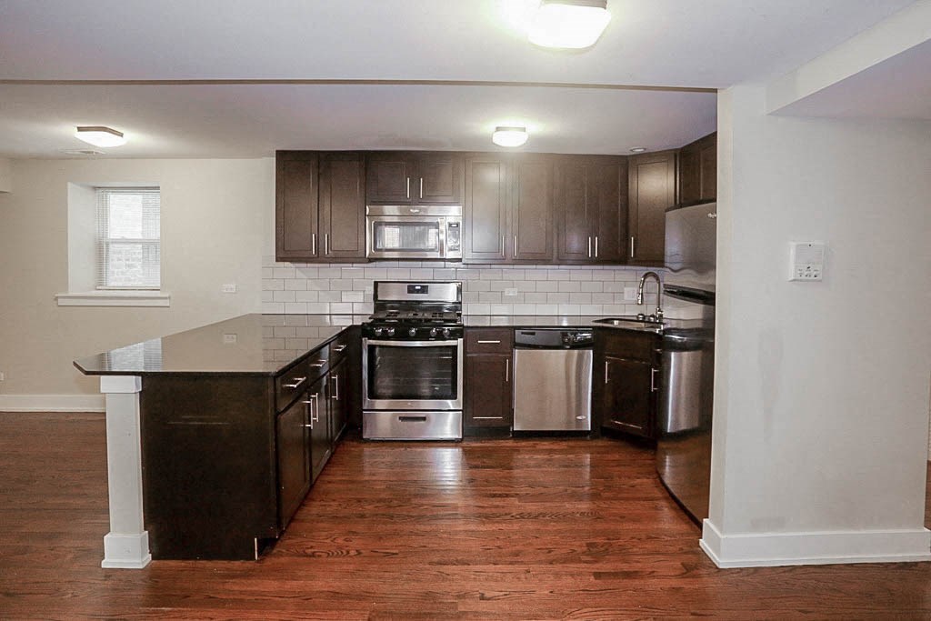 a kitchen with wooden floors and stainless steel appliances