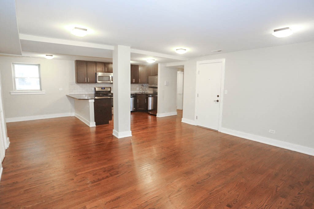 an empty living room and kitchen with wood floors