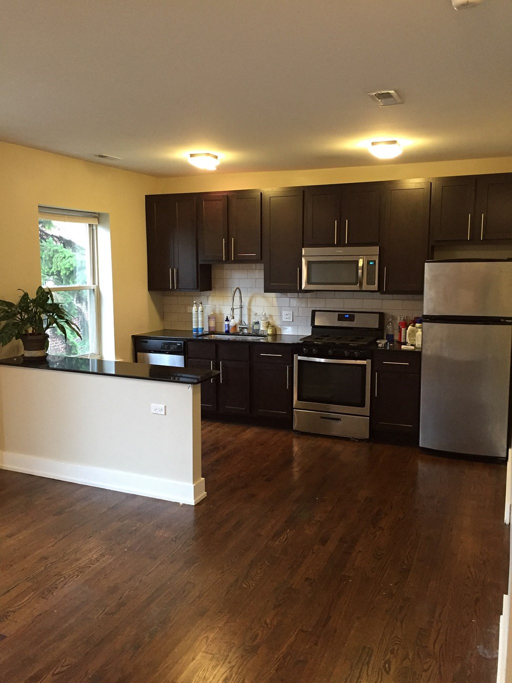 an empty kitchen with black cabinets and stainless steel appliances