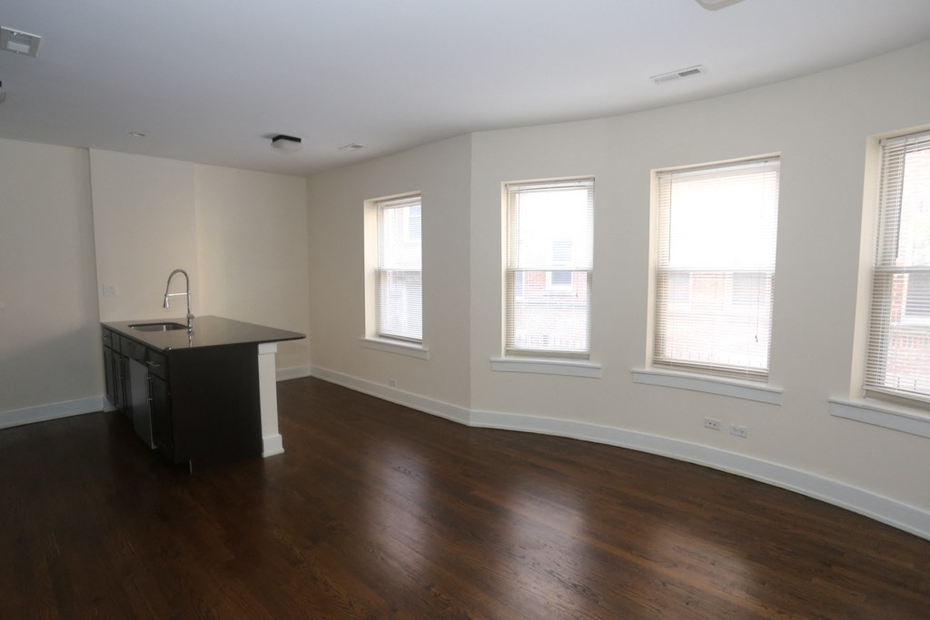 an empty living room with wood flooring and windows
