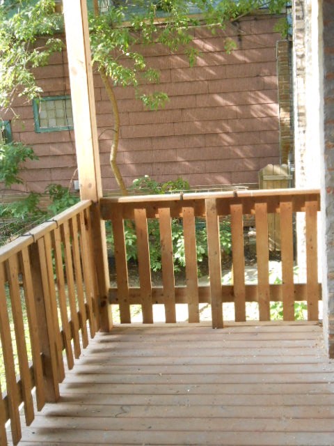 a porch with a wooden railing and a house in the background