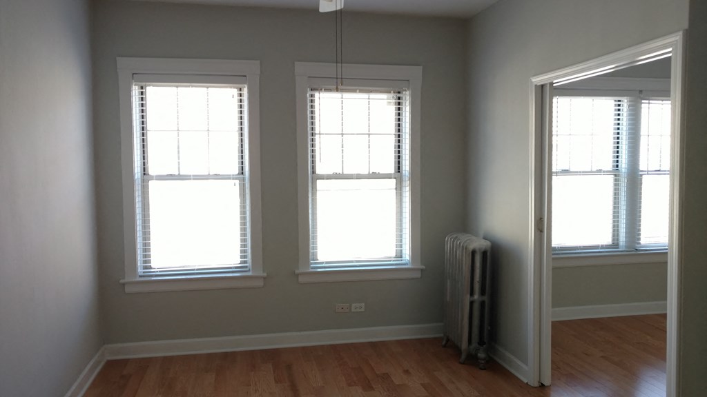 three windows in a room with a wood floor and a radiator