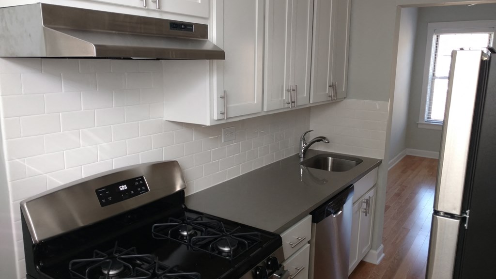 a kitchen with white cabinets and a stove and a sink