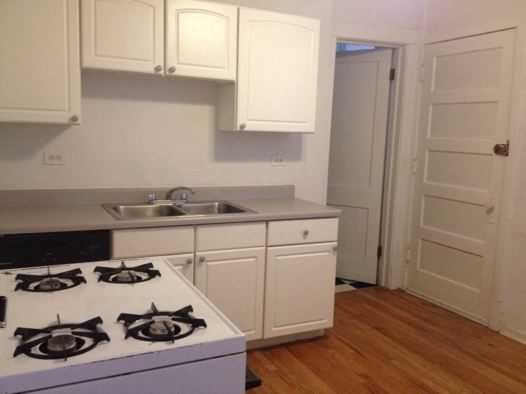 a kitchen with white cabinets and a stove and a sink