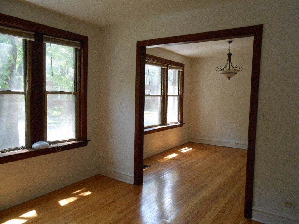 an empty room with a wood floor and two windows