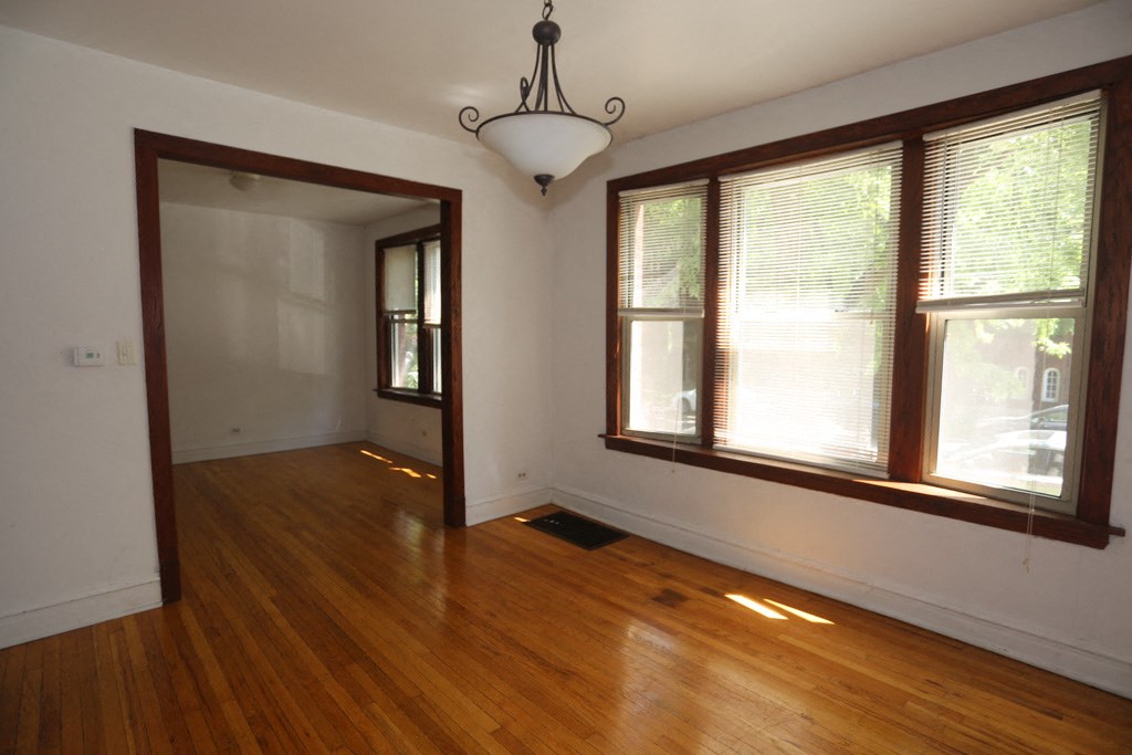 an empty living room with wood floors and large windows