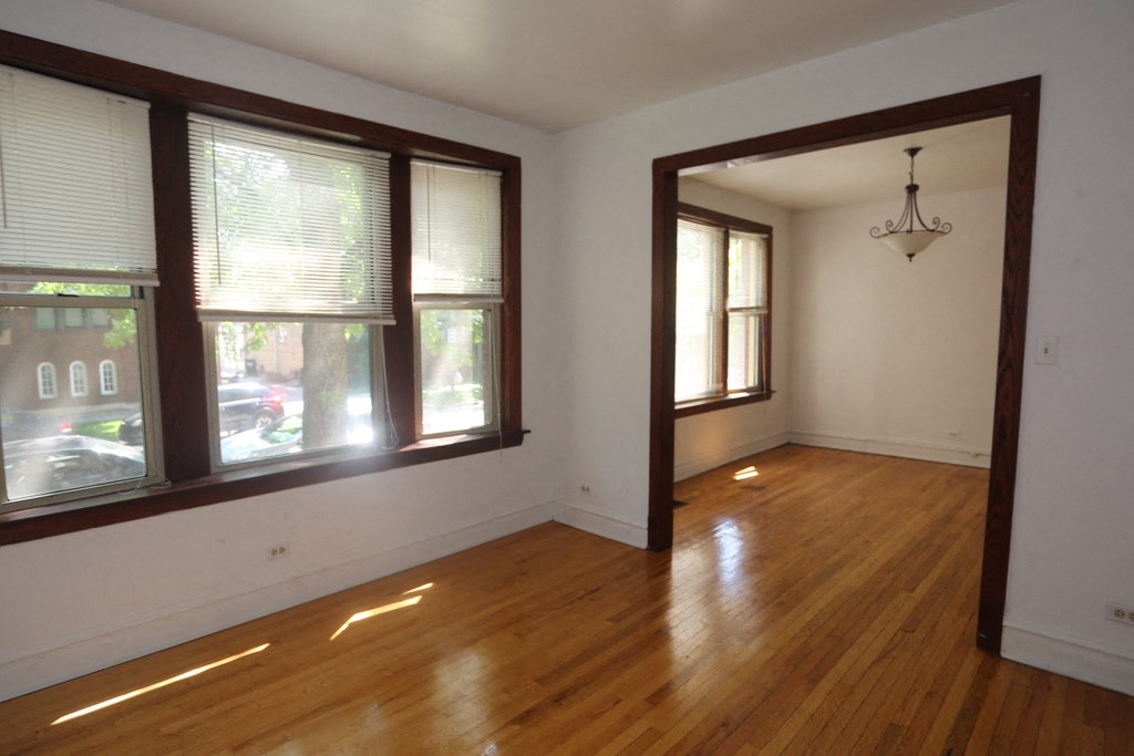 an empty living room with wood floors and large windows
