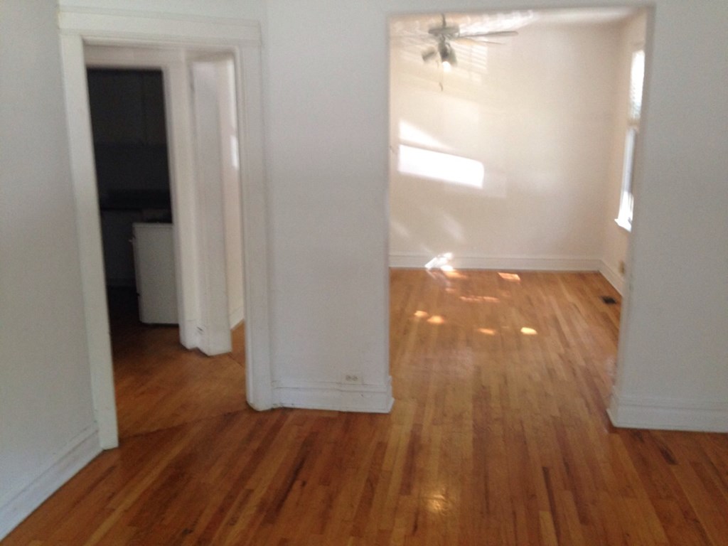 an empty living room with a hard wood floor and white walls