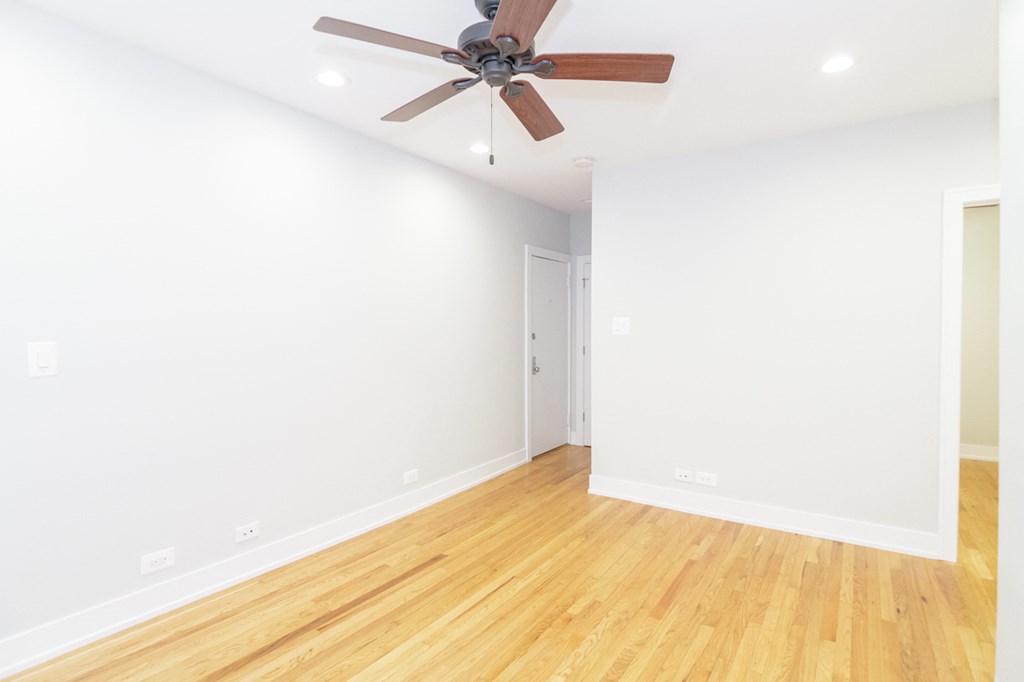an empty room with white walls and a ceiling fan