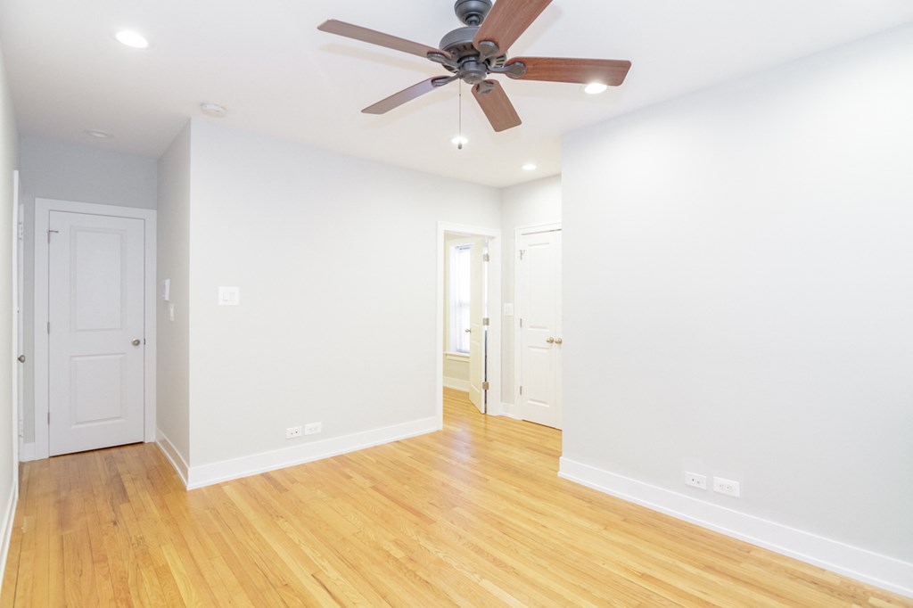 a living room with white walls and a ceiling fan
