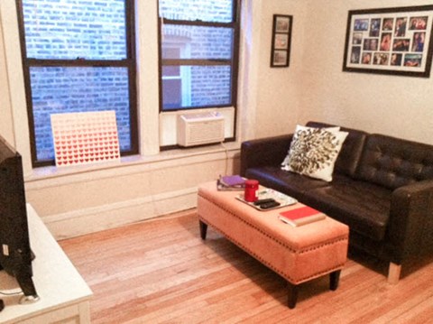 a living room with a leather couch and an orange ottoman