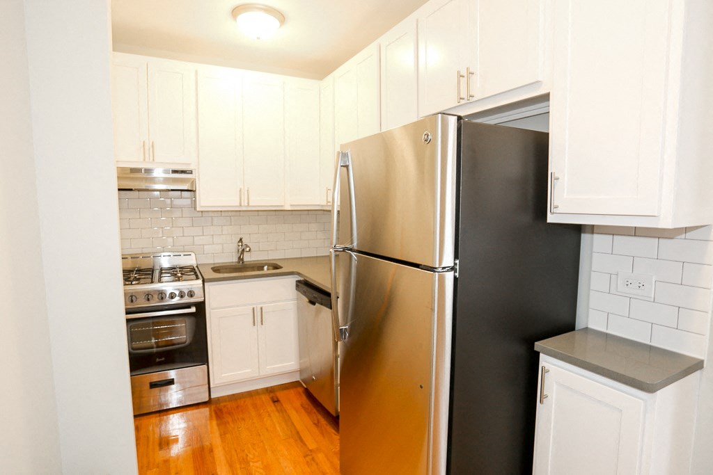 a kitchen with white cabinets and a stainless steel refrigerator