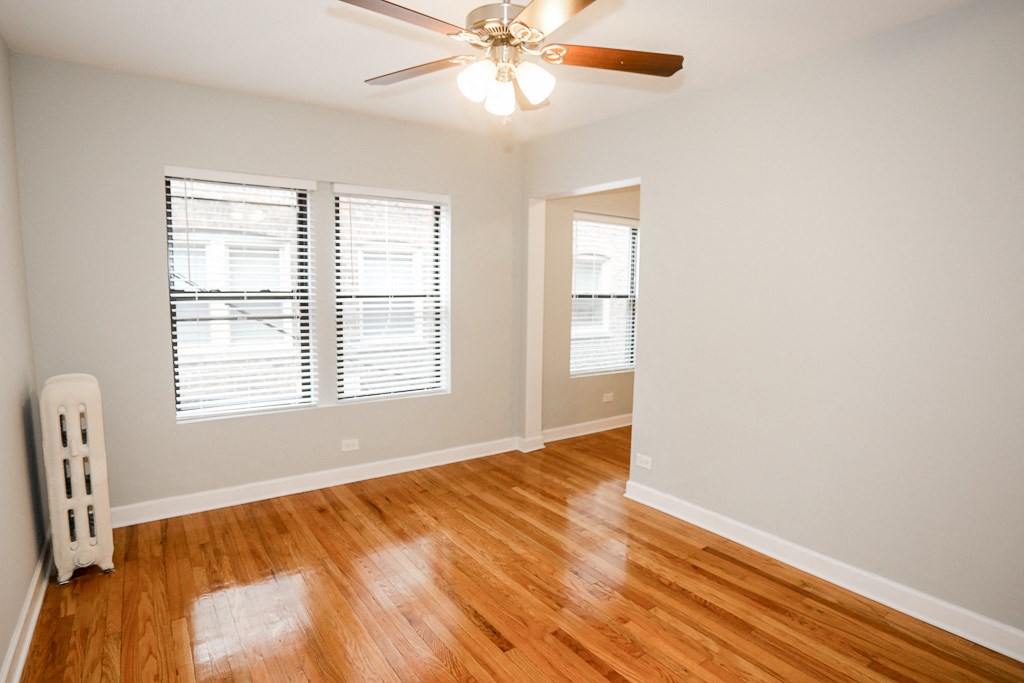 an empty living room with wood floors and a ceiling fan