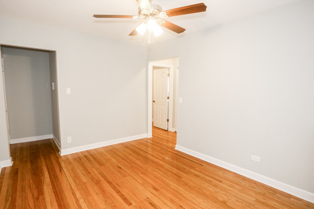 an empty living room with wood floors and a ceiling fan