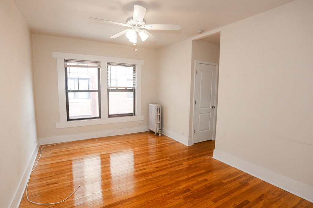 an empty living room with wood floors and a ceiling fan