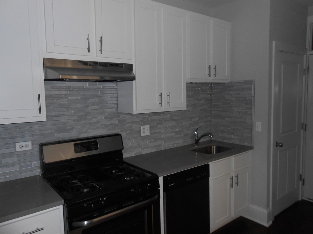 a kitchen with white cabinets and a stove and a sink