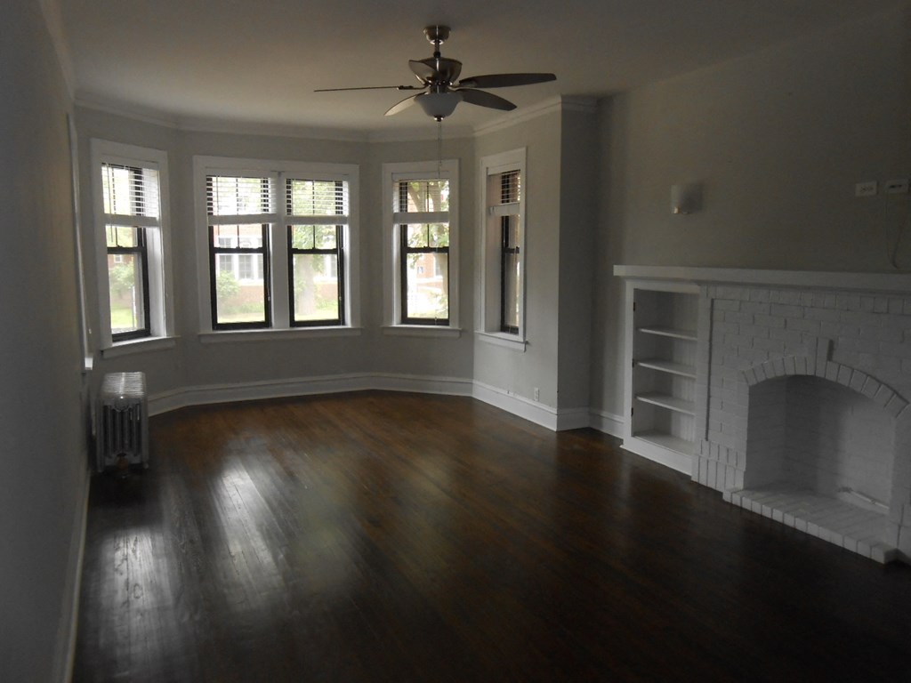 an empty living room with a fireplace and wooden floors