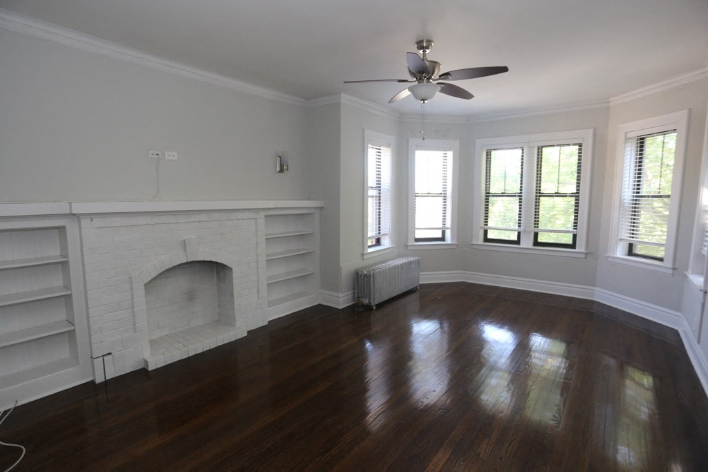 an empty living room with a fireplace and wooden floors