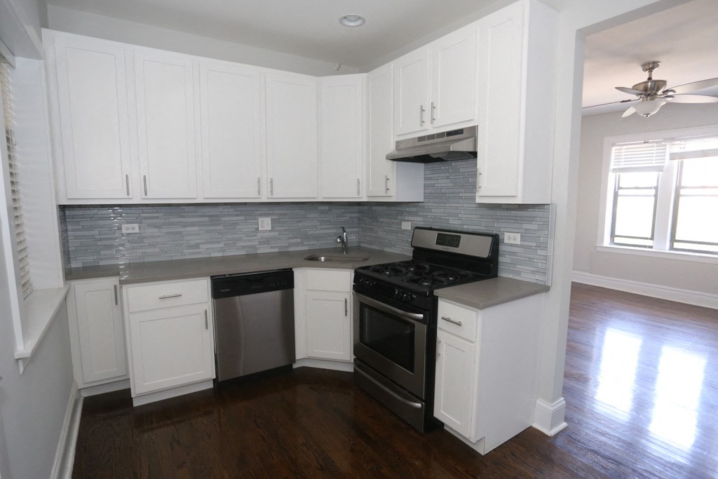 an empty kitchen with white cabinets and a black stove