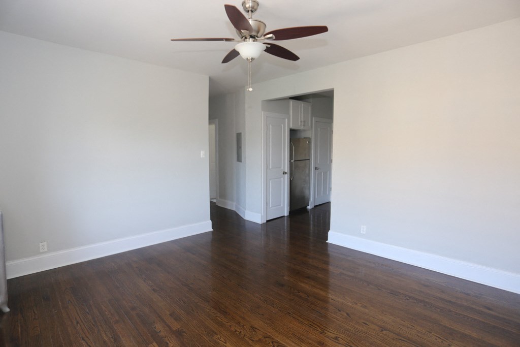 an empty living room with wood floors and a ceiling fan