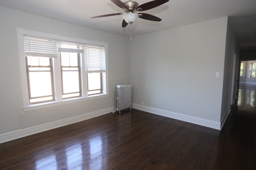 an empty living room with wood floors and a ceiling fan