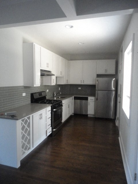 an empty kitchen with white cabinets and stainless steel appliances