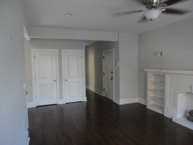 an empty living room with wooden floors and white doors