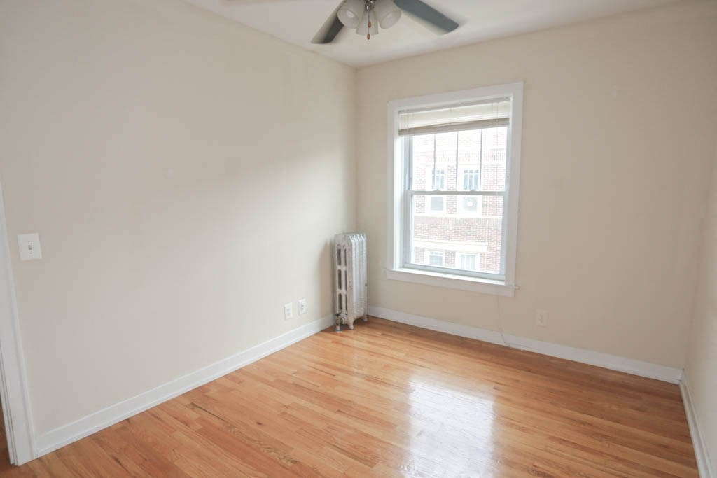 a room with wooden floors and a window and a ceiling fan