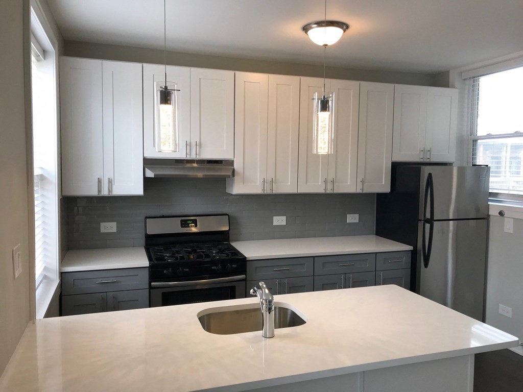 a kitchen with white counter tops and black appliances