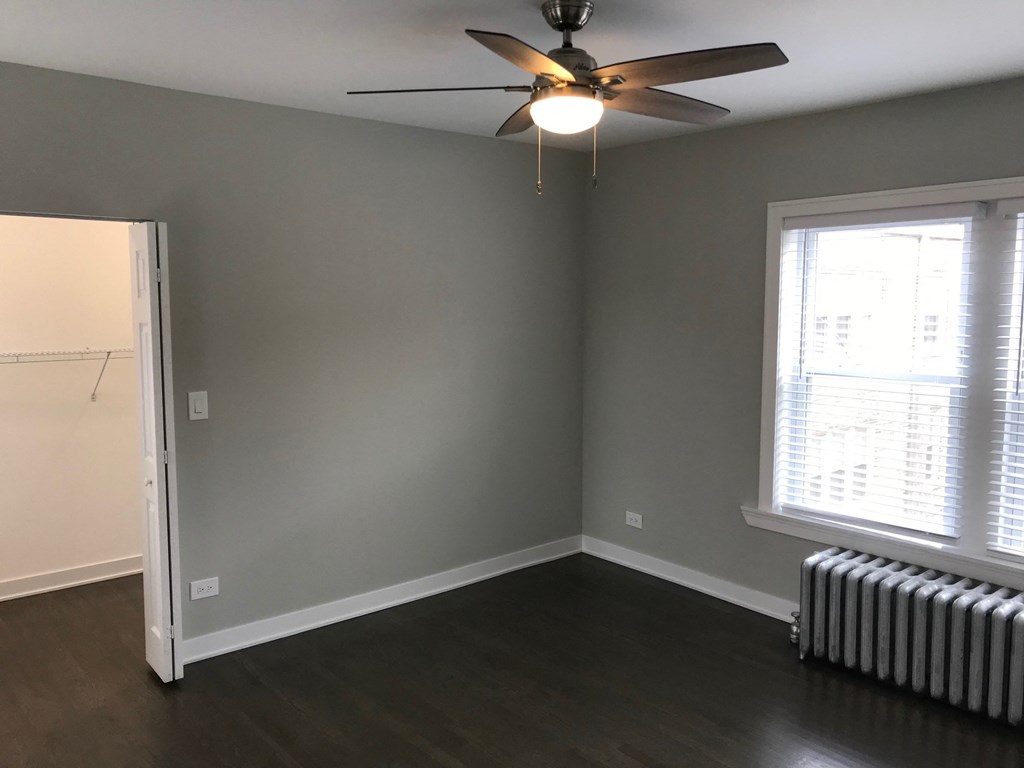 an empty room with a ceiling fan and a radiator