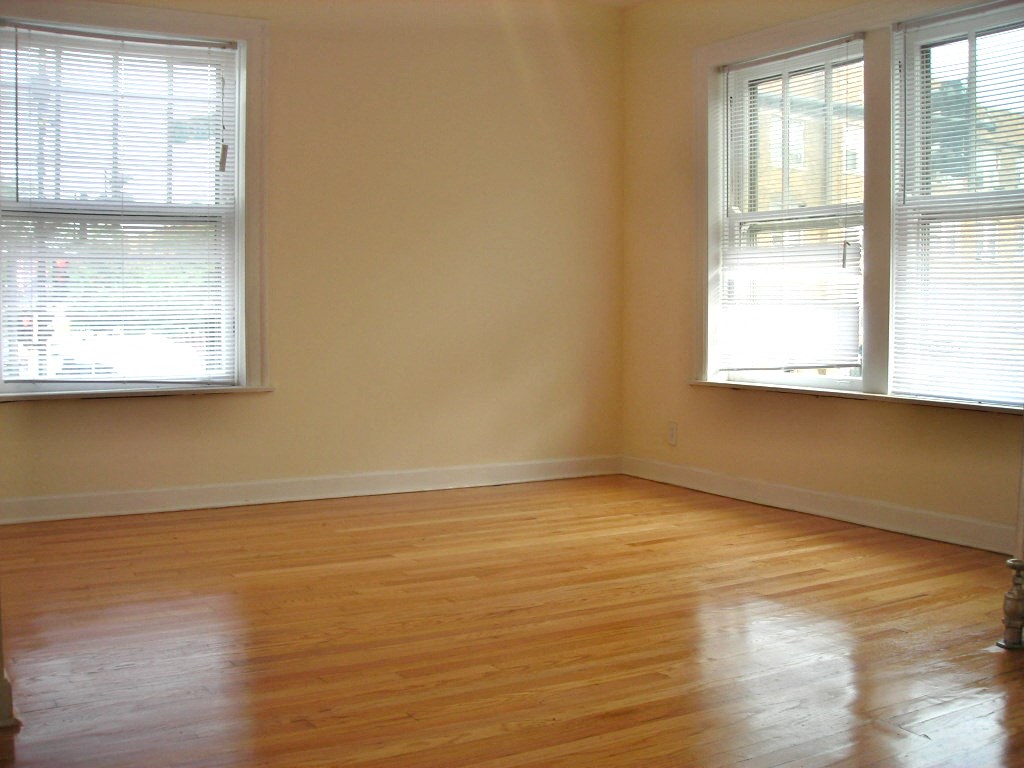 an empty room with wood floors and two windows