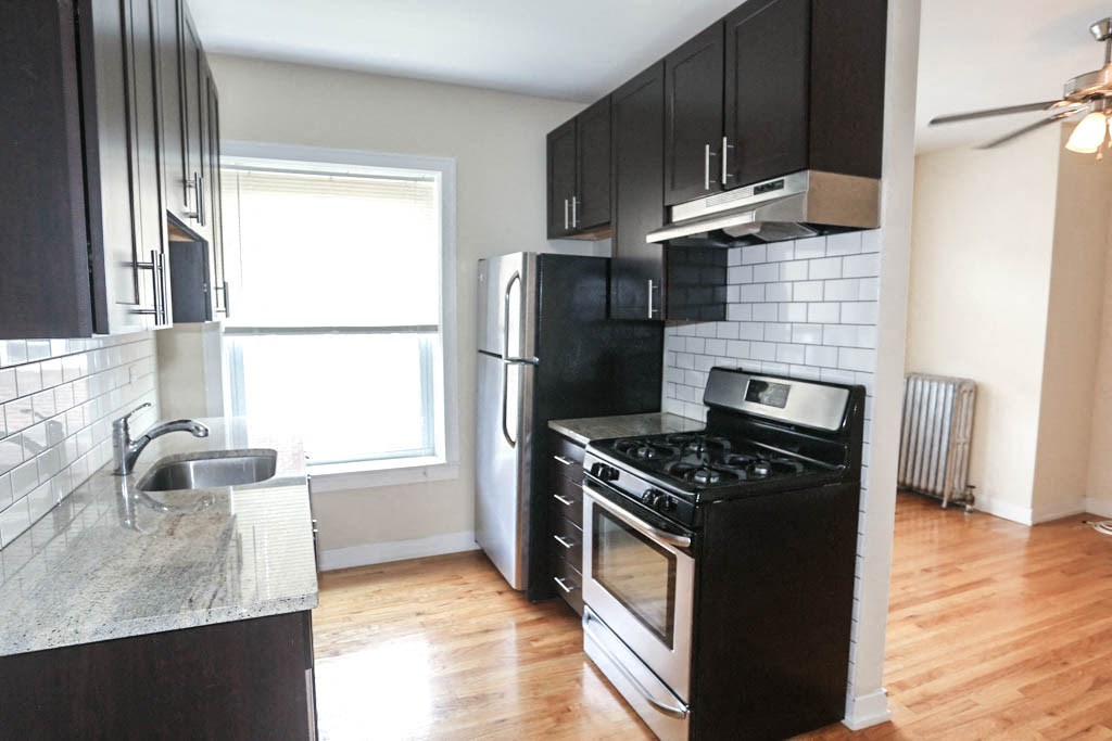 an empty kitchen with black and white appliances and wood floors