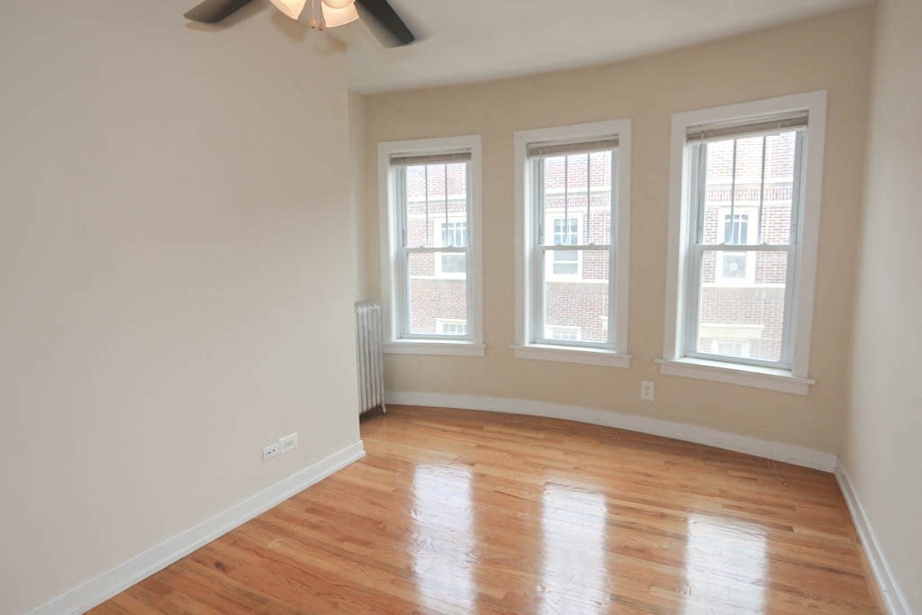 an empty room with a wood floor and three windows
