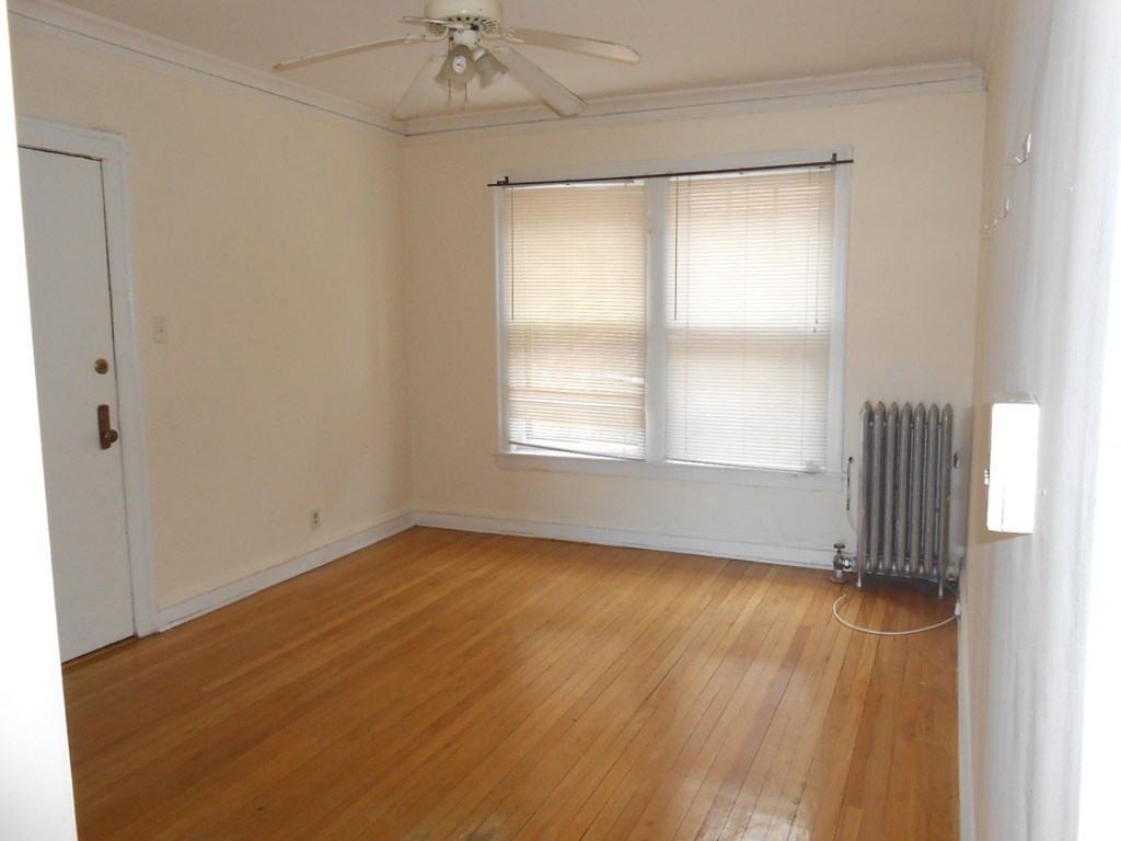an empty living room with wood floors and a radiator