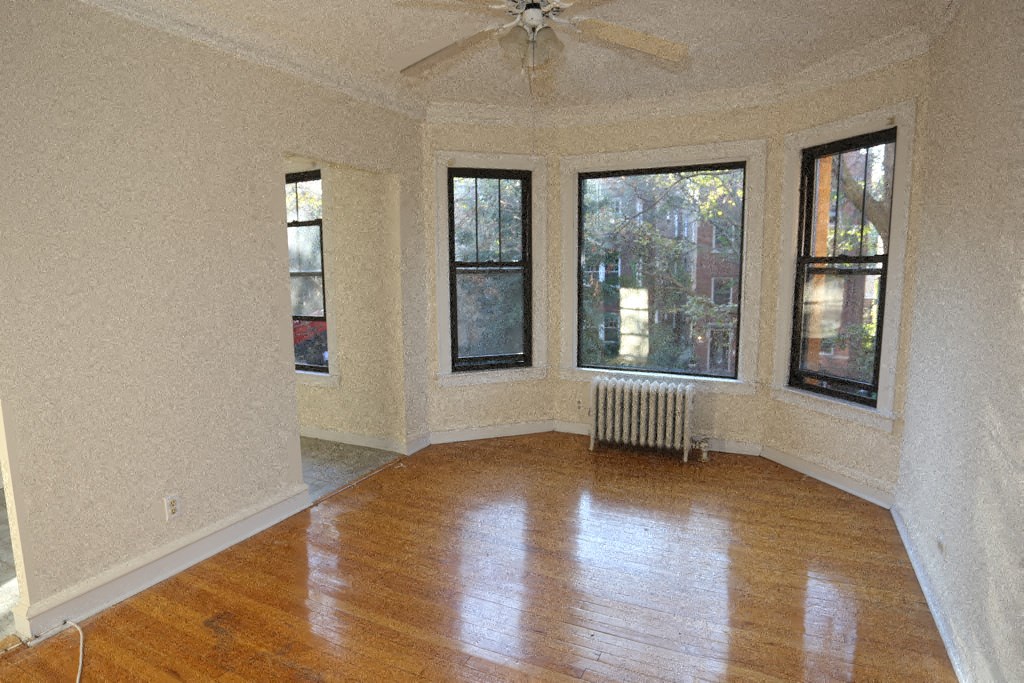 an empty living room with a wood floor and a ceiling fan