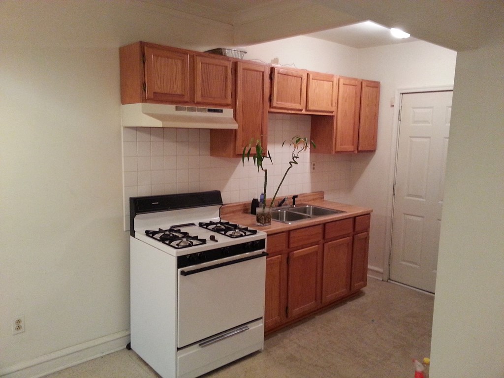 an empty kitchen with white appliances and wooden cabinets