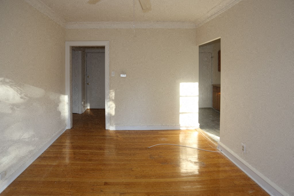 an empty living room with wood floors and white walls