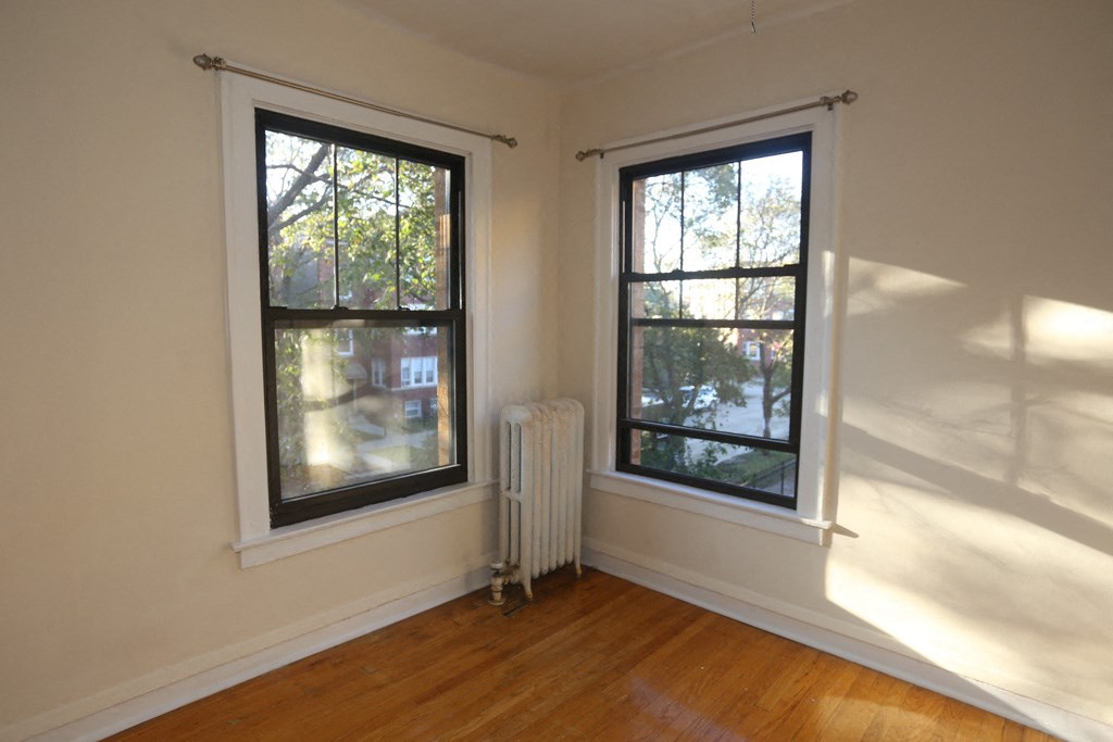 an empty room with two windows and a radiator