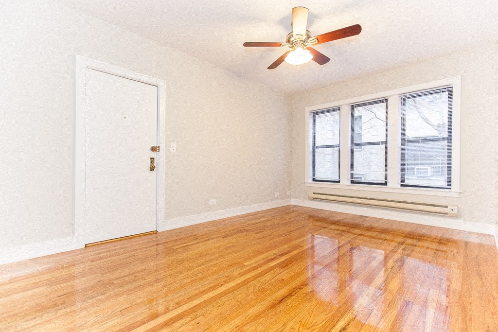 an empty living room with a ceiling fan and a window