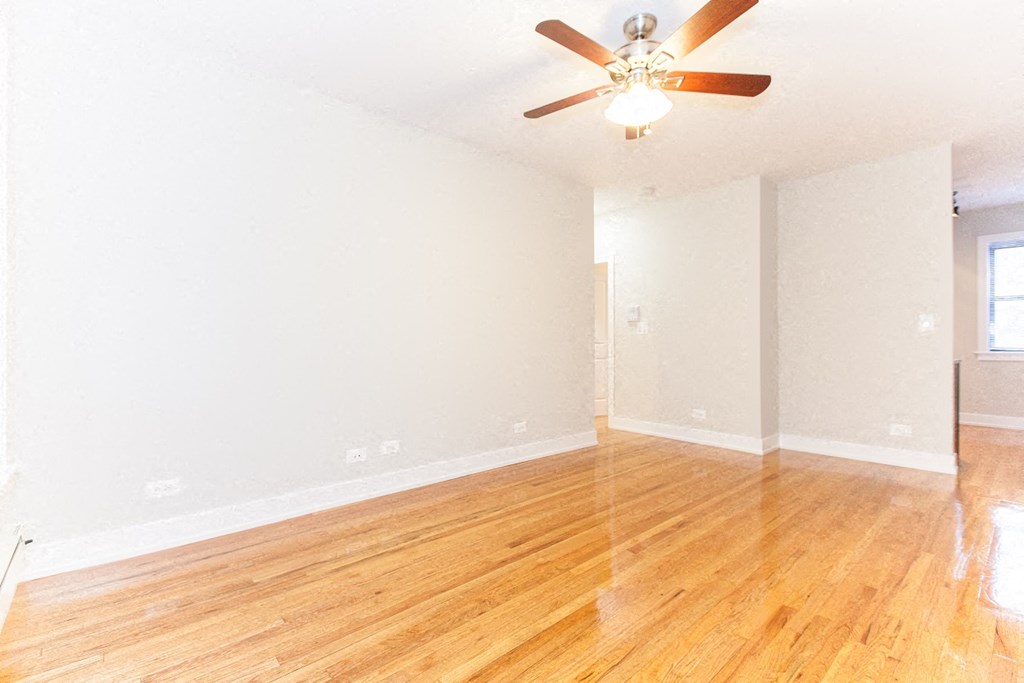 an empty living room with wood floors and a ceiling fan