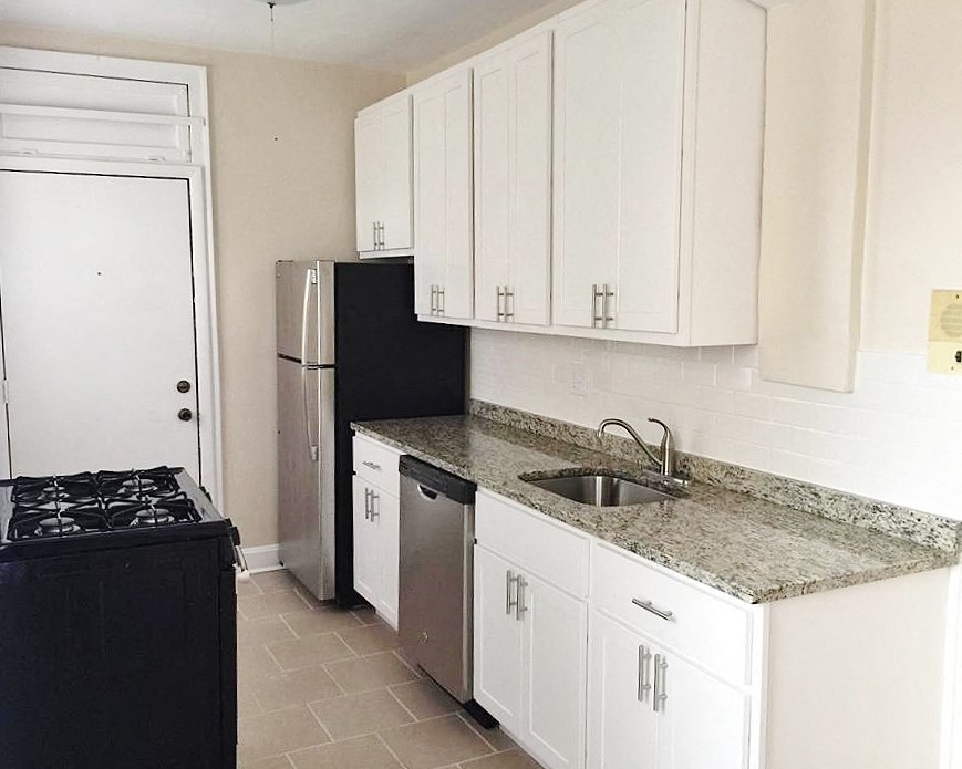 a kitchen with white cabinets and a sink and a refrigerator