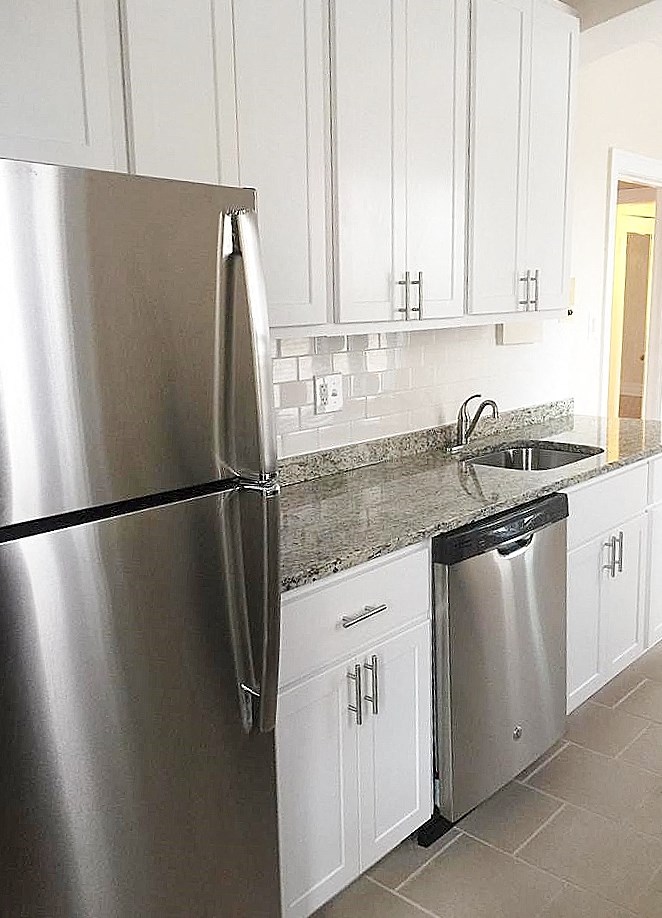 a kitchen with white cabinets and a stainless steel refrigerator