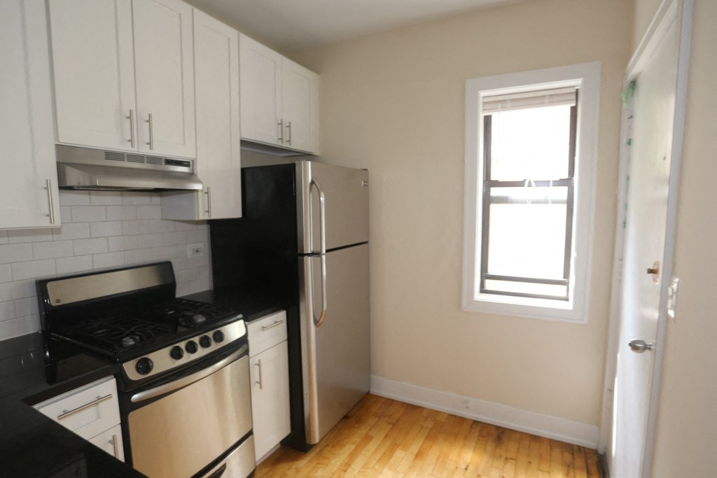 an empty kitchen with a stove refrigerator and a window