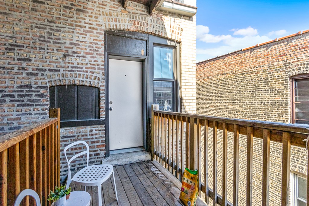 a balcony with a white door and a patio with chairs