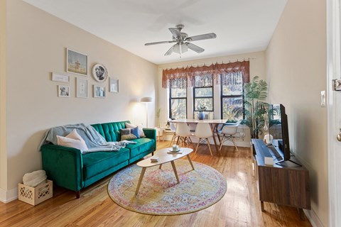 a living room with a green couch and a ceiling fan