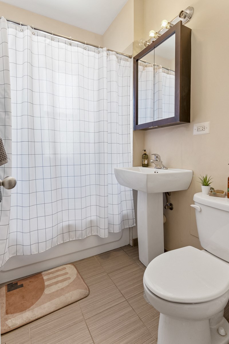 a bathroom with a toilet and a sink and a shower curtain