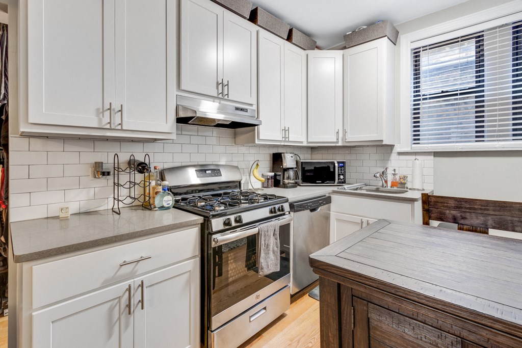 a kitchen with white cabinets and stainless steel appliances
