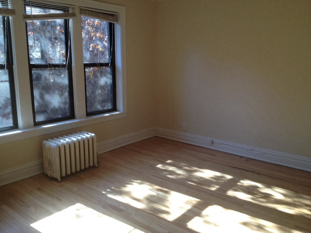 an empty room with a heater and two windows