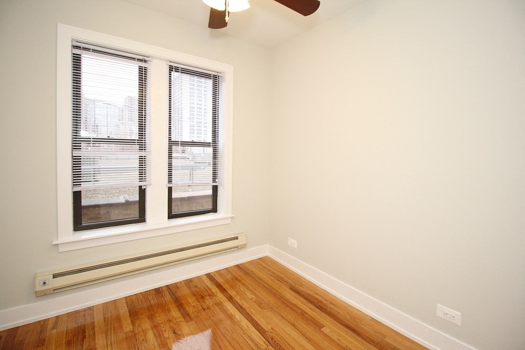 an empty room with two windows and a hard wood floor